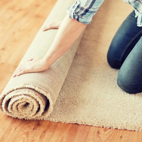 woman rolling up a beige carpet