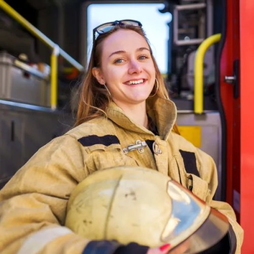 smiling firefighter holding her helmet